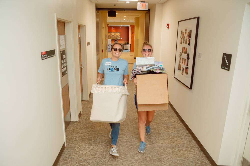 two females carry boxes
